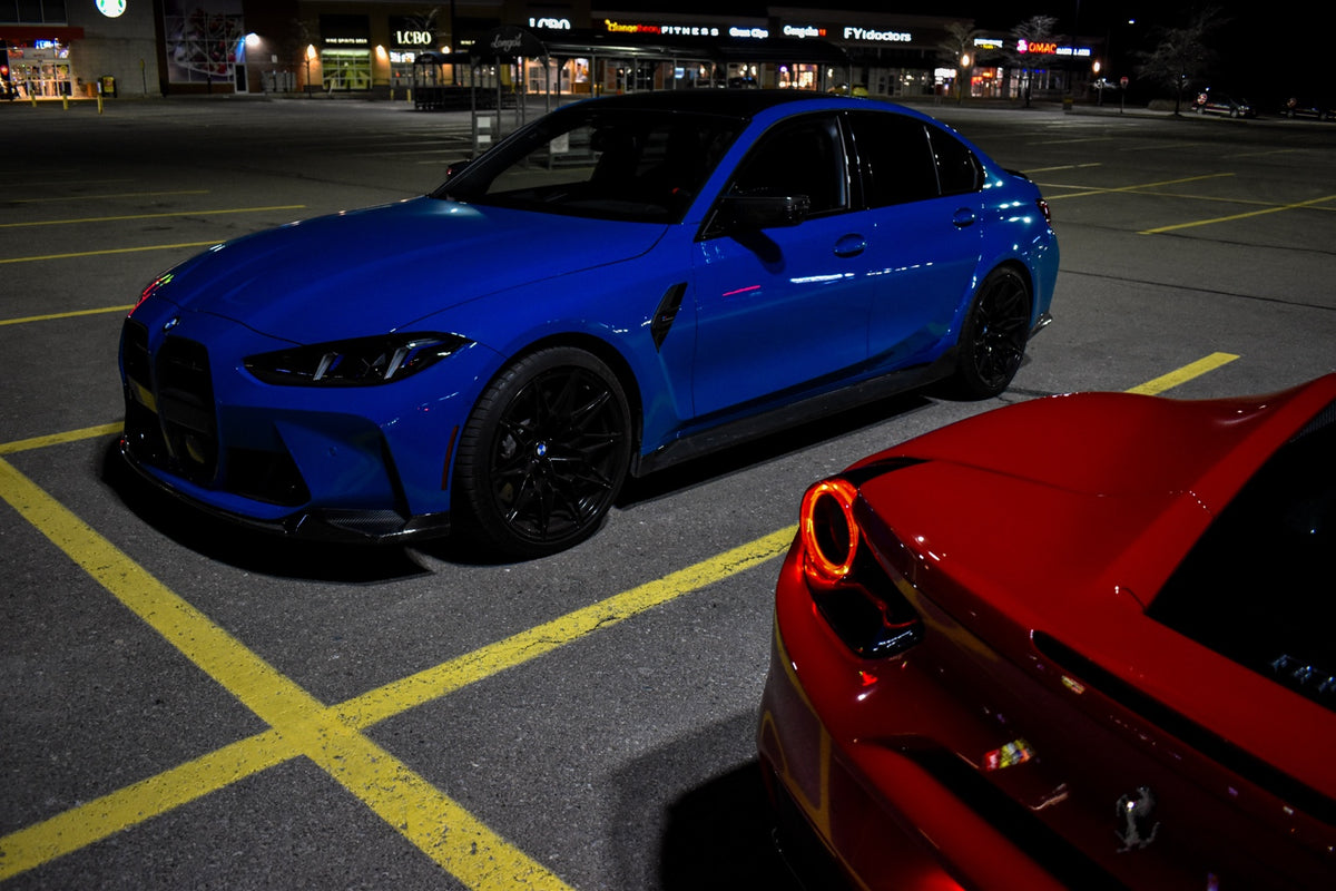 Blue BMW M3 beside a red Ferrari at night